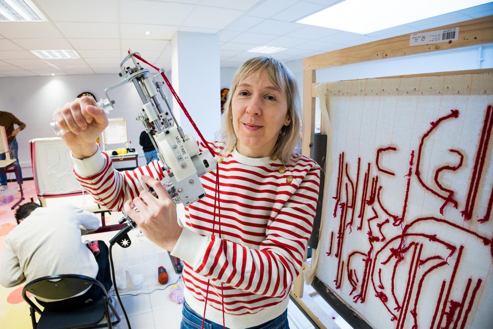 Je stikt of ‘schiet’ de garen op het doek met een soort draagbare naaimachine, zoals hier in het atelier van Mieke Van Steenkiste.