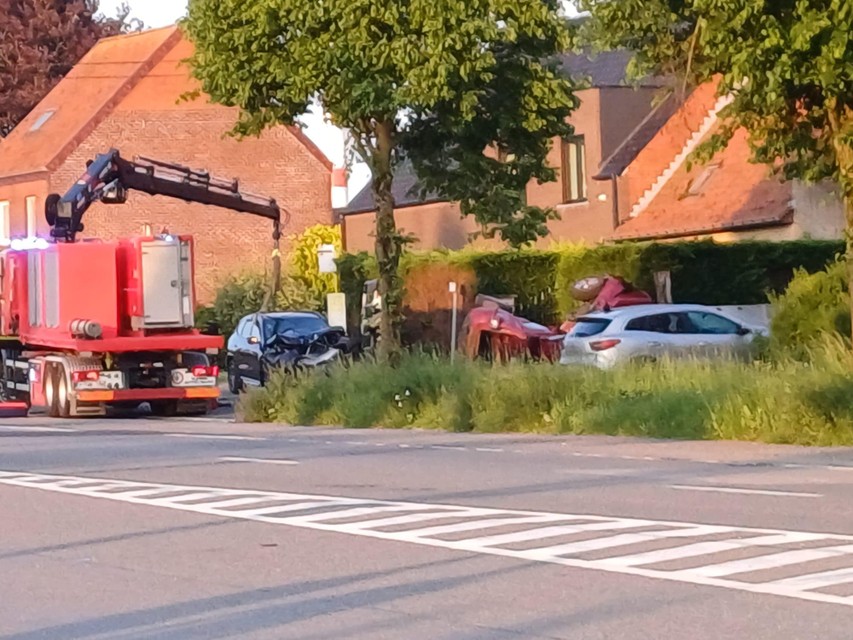 De BMW wordt weggetakeld, de geparkeerde rode auto is compleet verwoest.