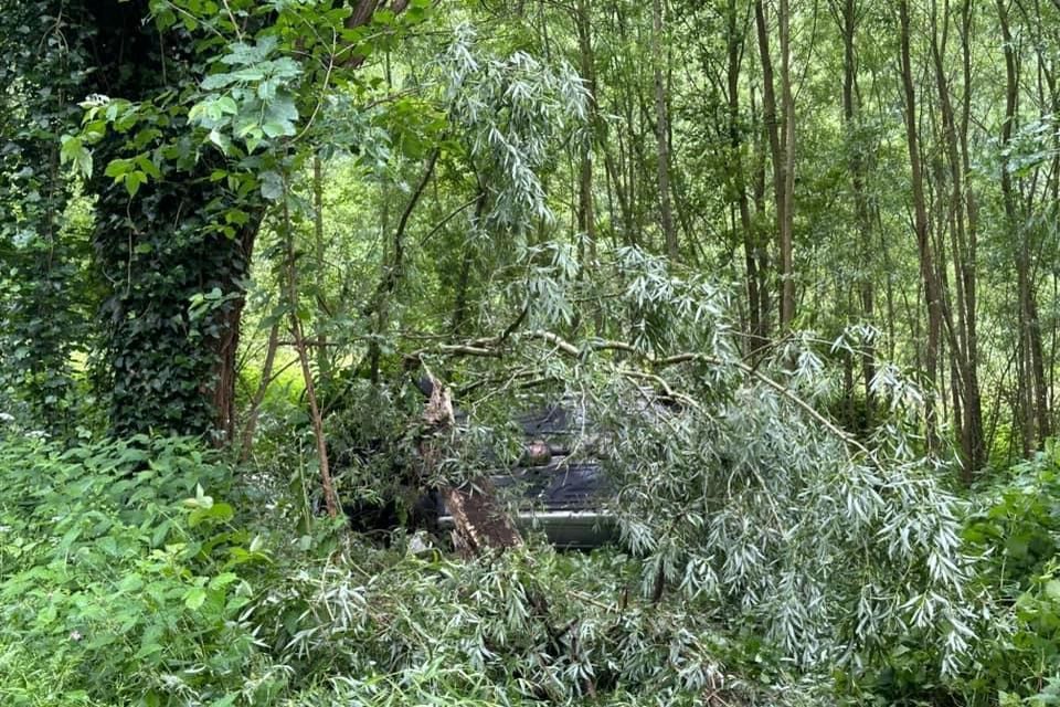 Een toevallige passant merkte een auto op zijn dak tussen de bomen en verwittigde de hulpdiensten.